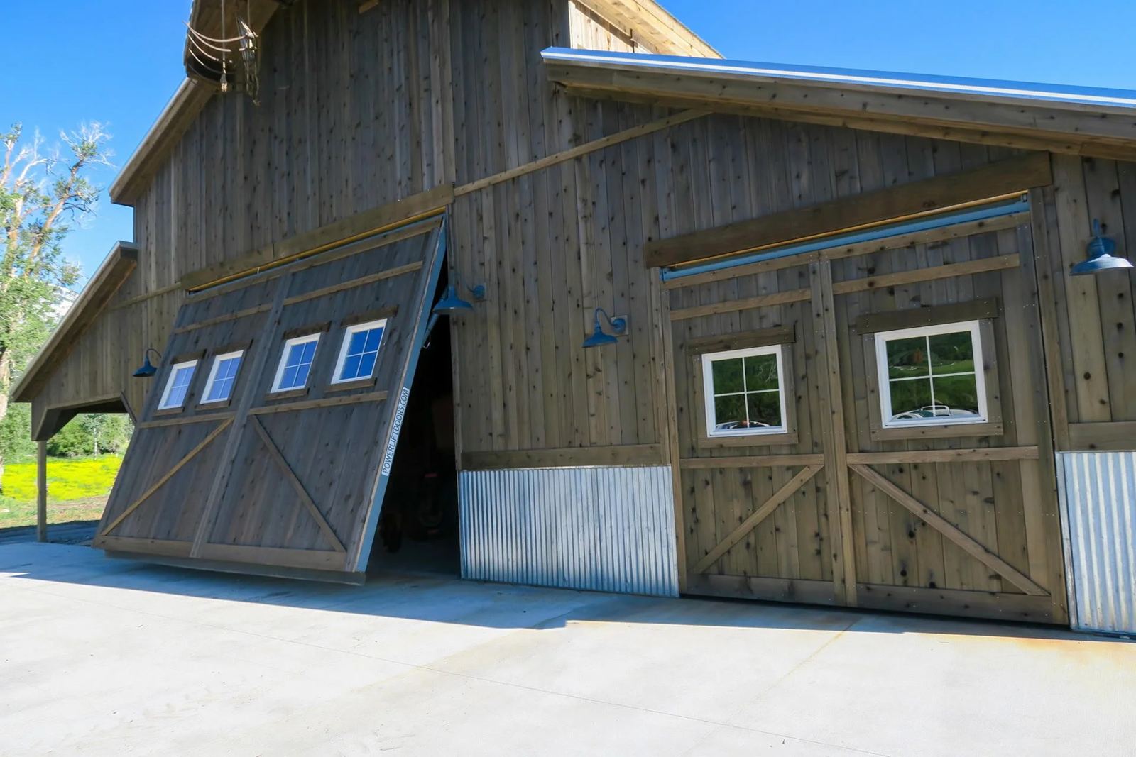 Cedar-clad hydraulic door with windows raised on a wood barn