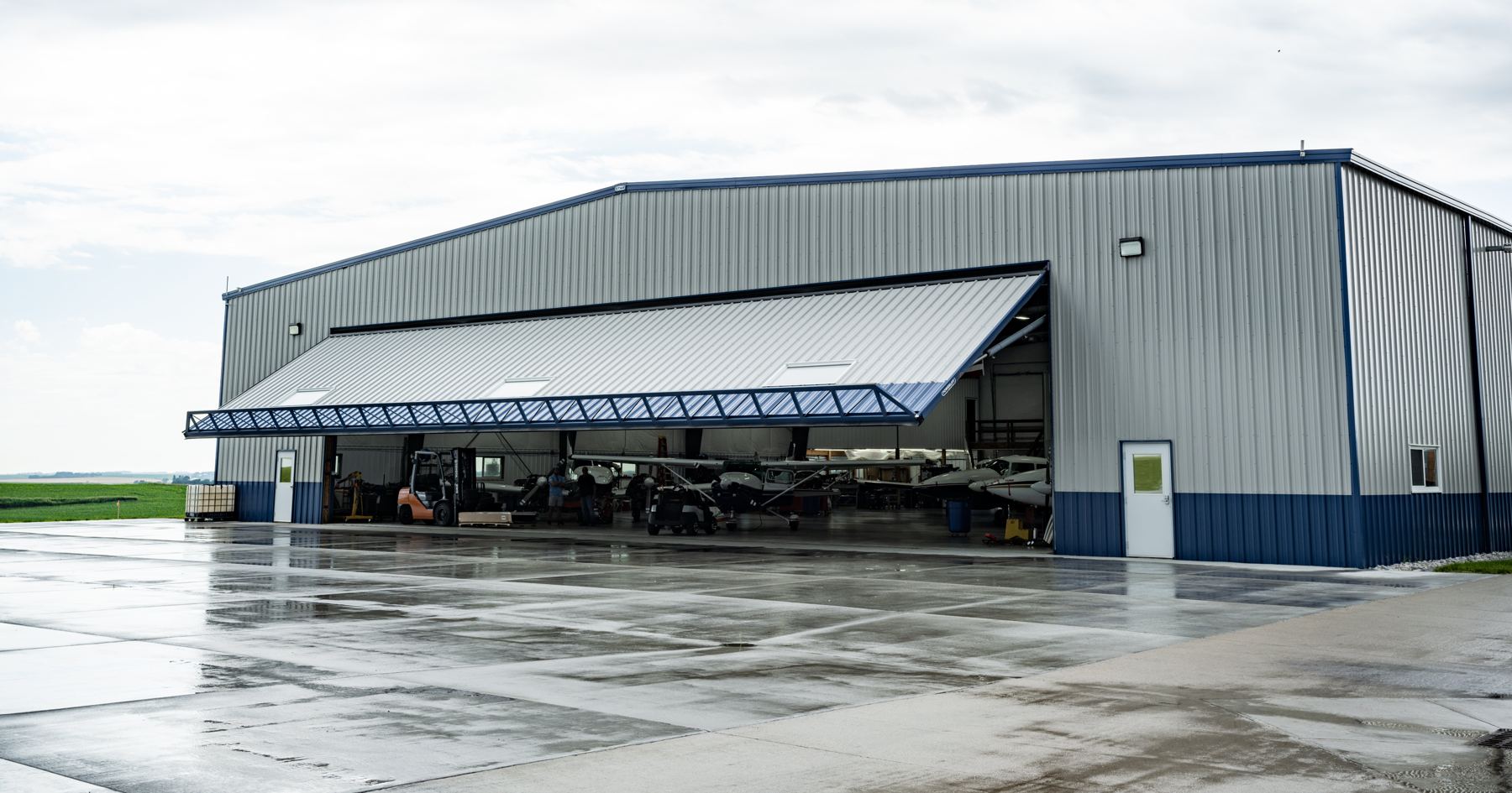 Steel hangar with its PowerLift hydraulic door raised and aircraft inside