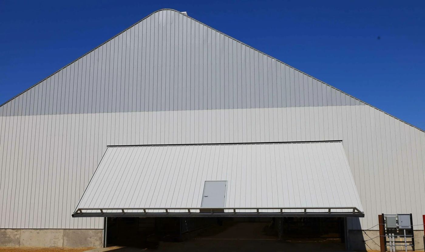 Large one-piece hydraulic door open on a white steel building